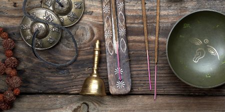 Tibetan singing bowl and other religious ritual instruments for meditation on a brown wooden background, top view