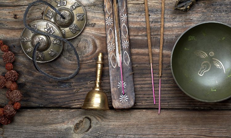 Tibetan singing bowl and other religious ritual instruments for meditation on a brown wooden background, top view